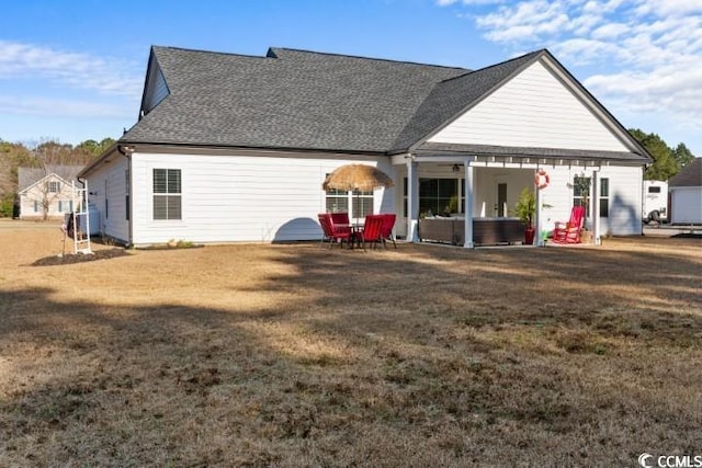 rear view of house featuring a patio area, roof with shingles, and a yard