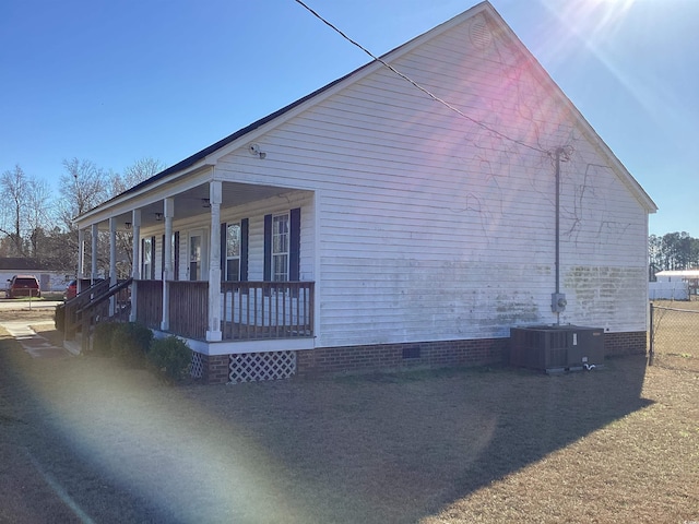 view of side of home with central AC, a porch, and crawl space