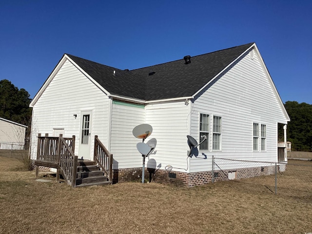 rear view of house with roof with shingles, a yard, and crawl space