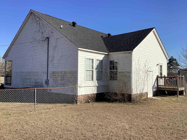 view of property exterior featuring roof with shingles, fence, and a deck