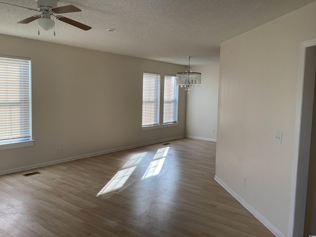 spare room featuring baseboards, a textured ceiling, visible vents, and wood finished floors