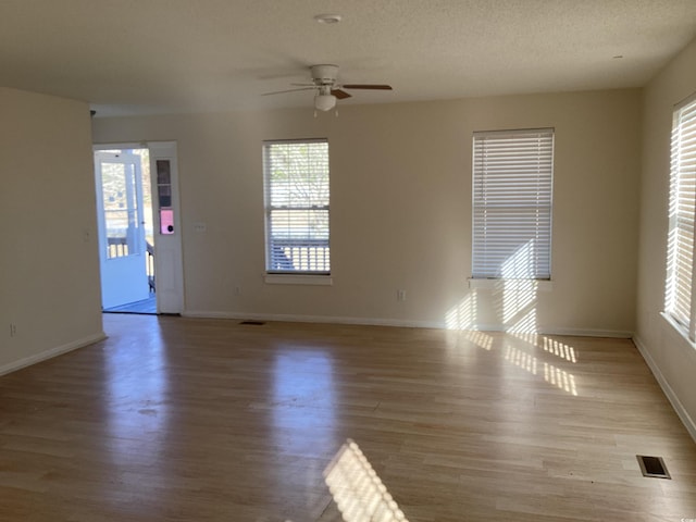 spare room featuring a textured ceiling, wood finished floors, visible vents, and baseboards