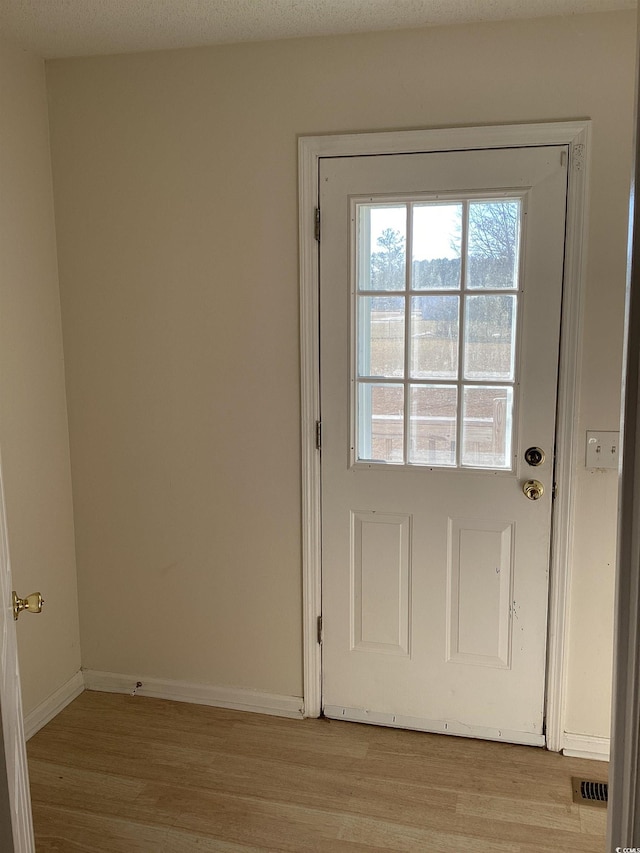 entryway with baseboards, visible vents, and light wood-style floors