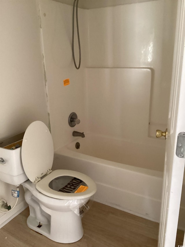 full bath featuring toilet, wood finished floors, and bathing tub / shower combination