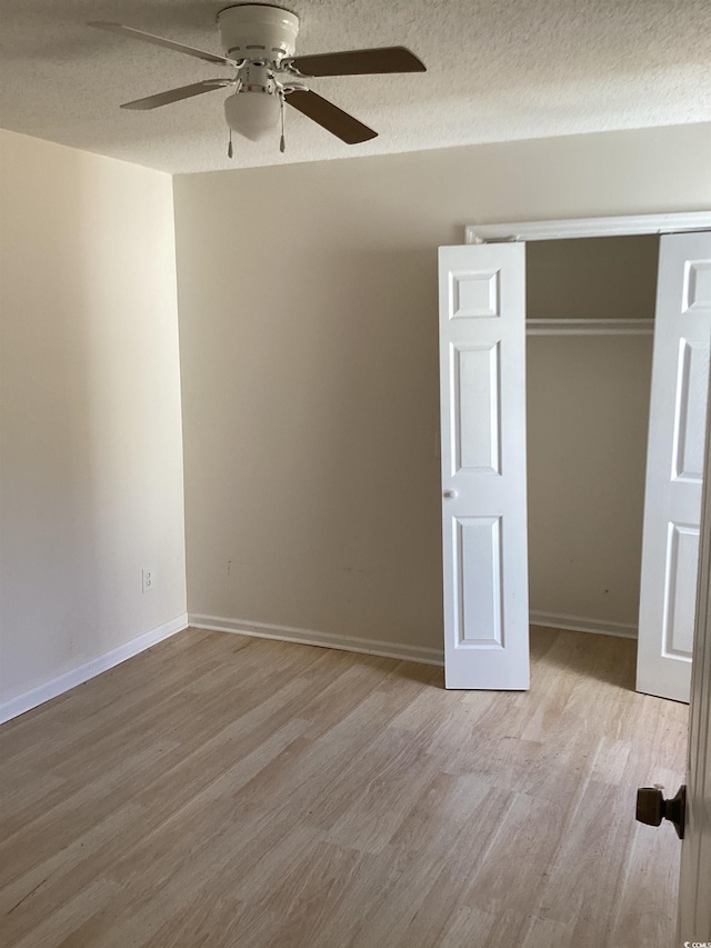 spare room featuring a textured ceiling, baseboards, a ceiling fan, and light wood-style floors