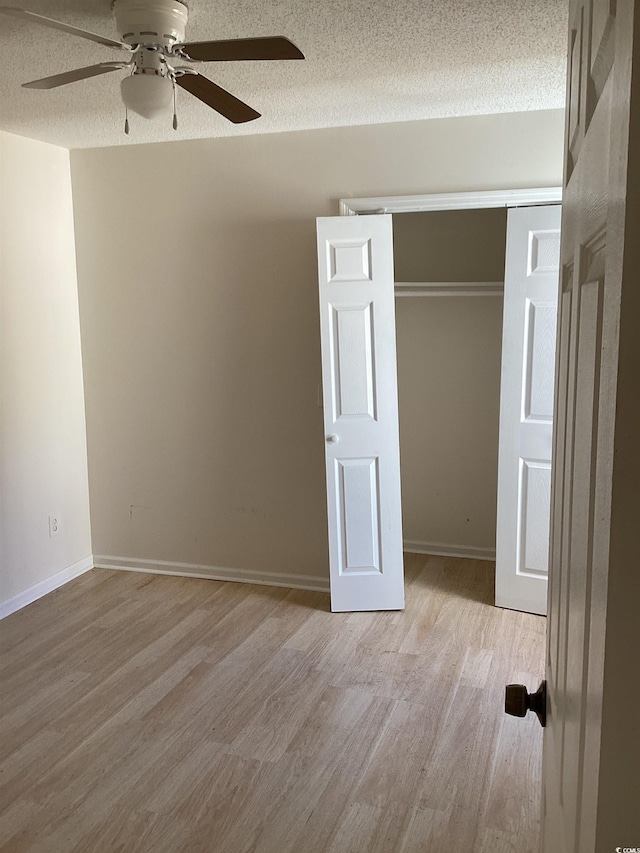 unfurnished bedroom with a textured ceiling, a closet, wood finished floors, and baseboards