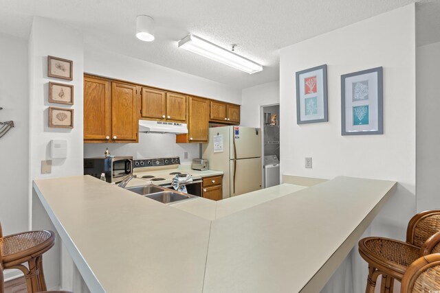 1000 N Waccamaw Dr Unit 205, Murrells Inlet, SC 29576 - kitchen with brown cabinets, white appliances, a kitchen breakfast bar, a peninsula, and under cabinet range hood