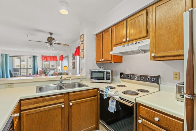 kitchen featuring under cabinet range hood, a sink, open floor plan, light countertops, and electric range oven