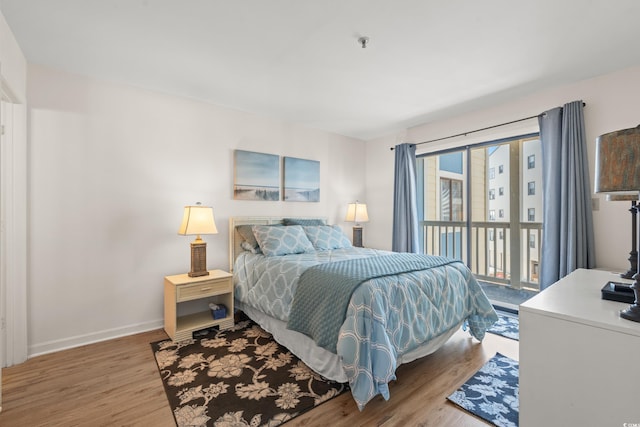 bedroom with access to outside, baseboards, and wood finished floors