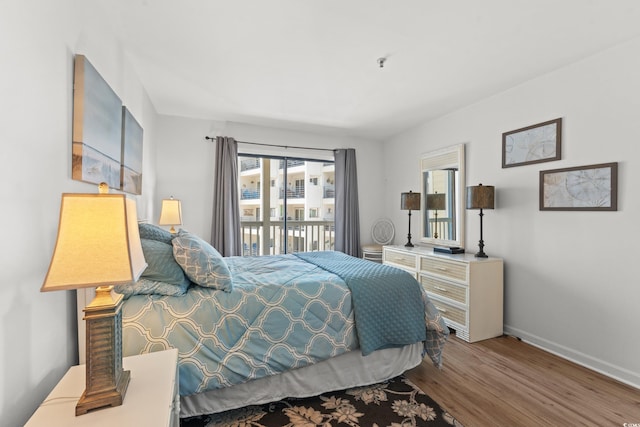 bedroom with access to outside, wood finished floors, and baseboards