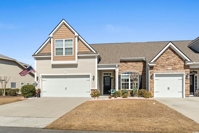 craftsman-style house featuring a front lawn, stone siding, and concrete driveway