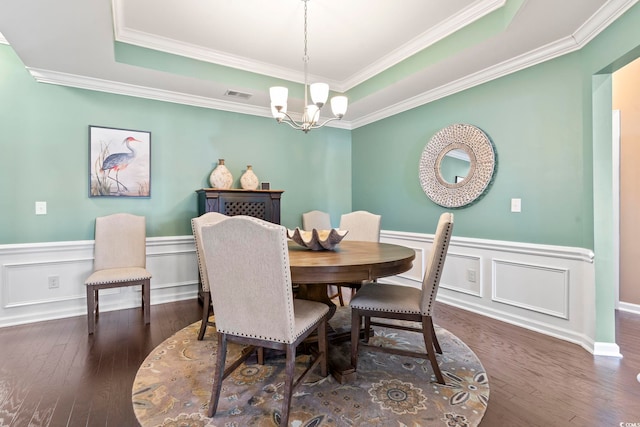 dining area with a chandelier, a wainscoted wall, dark wood-type flooring, visible vents, and a tray ceiling