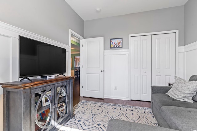 living room with a wainscoted wall, dark wood finished floors, and a decorative wall