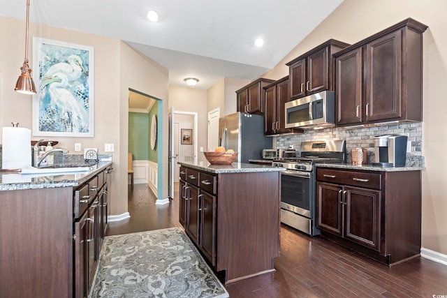 kitchen with hanging light fixtures, appliances with stainless steel finishes, light stone counters, and a sink