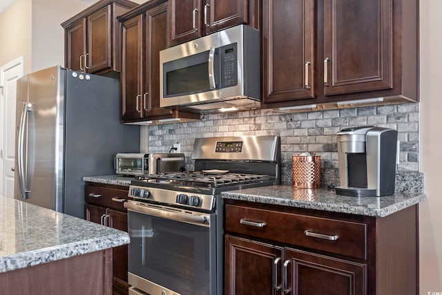 kitchen with dark brown cabinetry, a toaster, tasteful backsplash, light stone counters, and stainless steel appliances