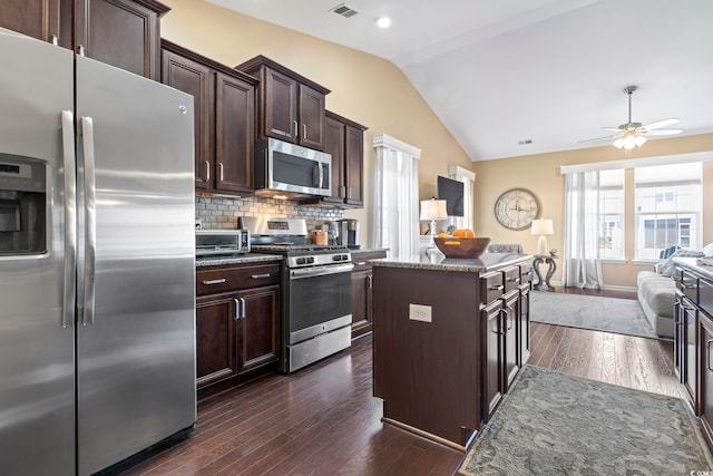 kitchen with dark brown cabinetry, open floor plan, vaulted ceiling, appliances with stainless steel finishes, and a center island