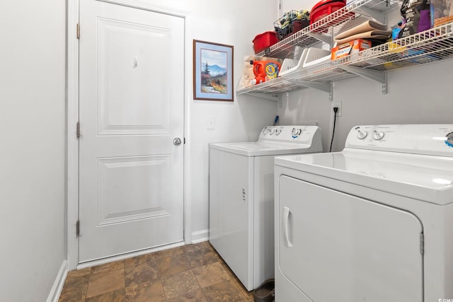 washroom featuring baseboards, laundry area, washing machine and dryer, and stone finish flooring