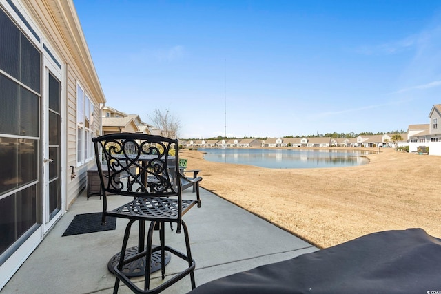 view of pool featuring a patio area, a water view, and a residential view