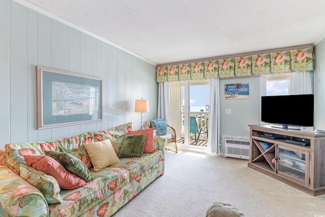 living room featuring a wall unit AC, carpet floors, ornamental molding, and a textured ceiling