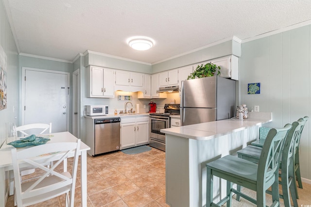 kitchen featuring white cabinets, under cabinet range hood, stainless steel appliances, and light countertops