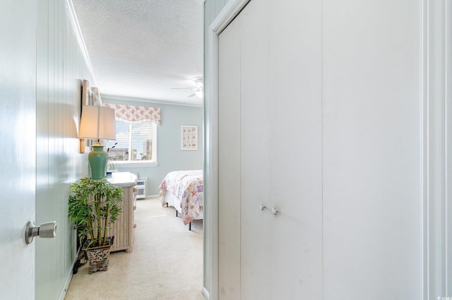 hallway with light carpet, ornamental molding, and a textured ceiling