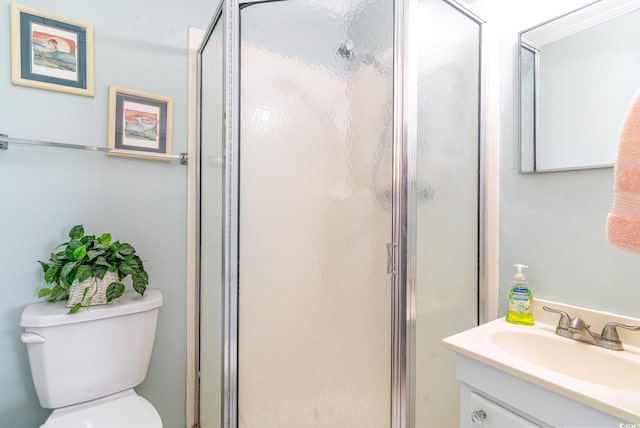 full bathroom with a stall shower, vanity, and toilet