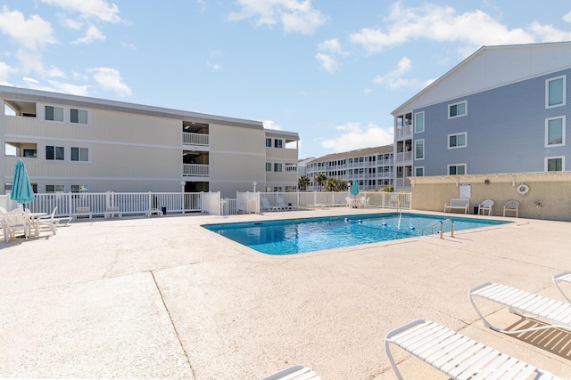 community pool with a patio area and fence