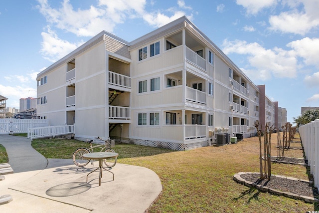 view of building exterior featuring fence and central AC