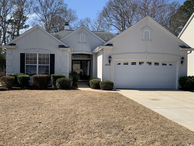 view of front facade with roof with shingles, a chimney, stucco siding, an attached garage, and driveway