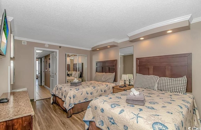 bedroom with a closet, crown molding, a textured ceiling, and wood finished floors