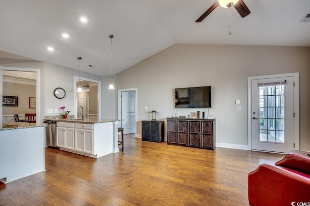 kitchen featuring decorative light fixtures, light wood finished floors, open floor plan, white cabinetry, and light stone countertops