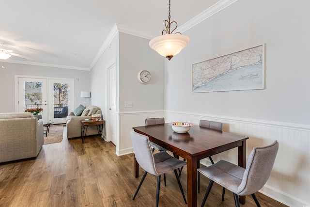 dining room with a wainscoted wall, a ceiling fan, ornamental molding, and wood finished floors