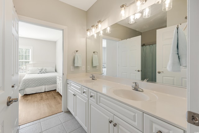 ensuite bathroom with ensuite bathroom, double vanity, tile patterned flooring, and a sink