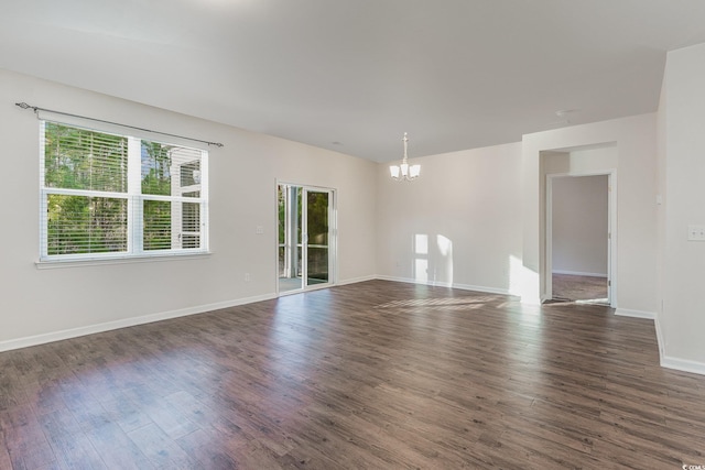 unfurnished room with baseboards, a chandelier, and dark wood-style flooring