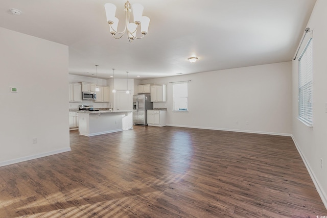 unfurnished living room with dark wood-style flooring, baseboards, and an inviting chandelier