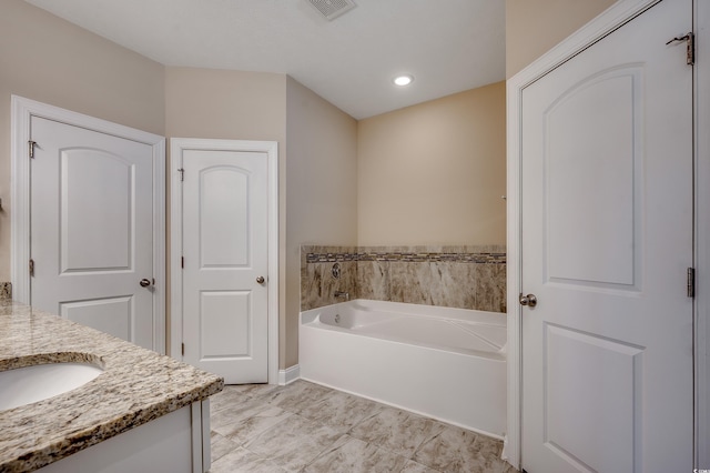 bathroom featuring visible vents, vanity, and a bath