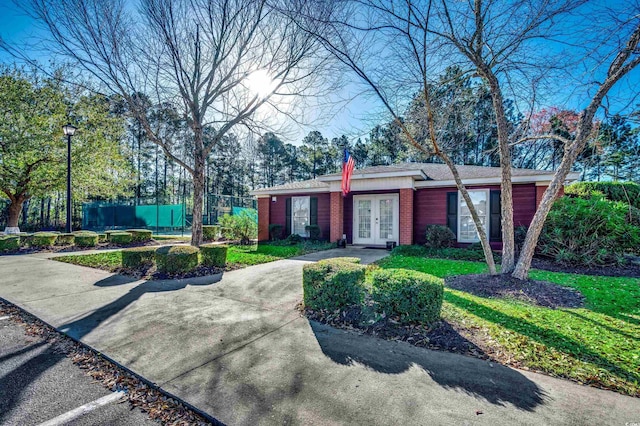 view of front of property with french doors, brick siding, and fence