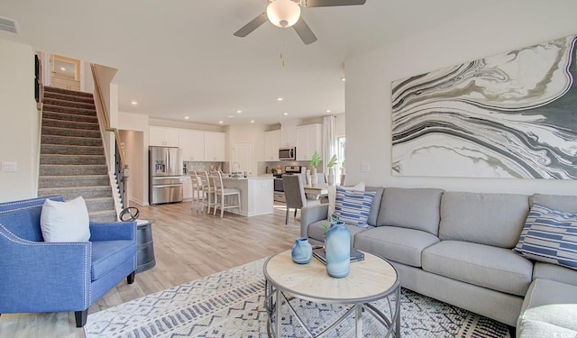 living room featuring visible vents, a ceiling fan, recessed lighting, stairway, and light wood-style floors