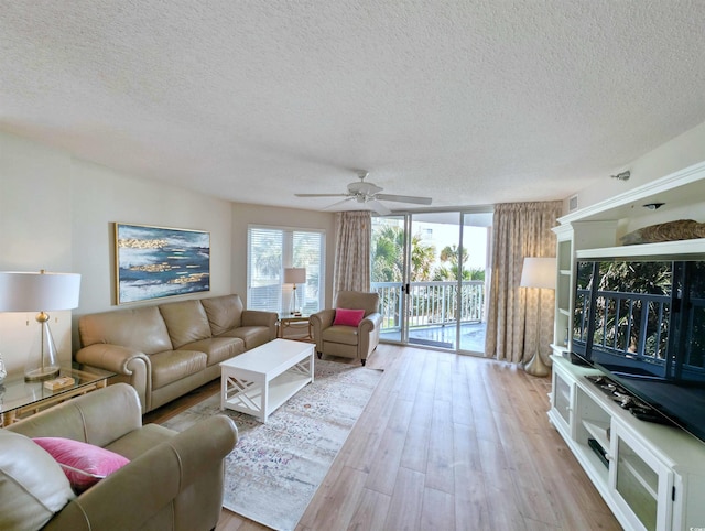 living area with a ceiling fan, floor to ceiling windows, light wood-style flooring, and a textured ceiling