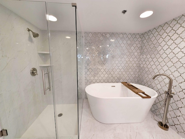 bathroom featuring a soaking tub, tile walls, a shower stall, and marble finish floor