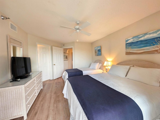 bedroom with light wood-type flooring, visible vents, and a ceiling fan