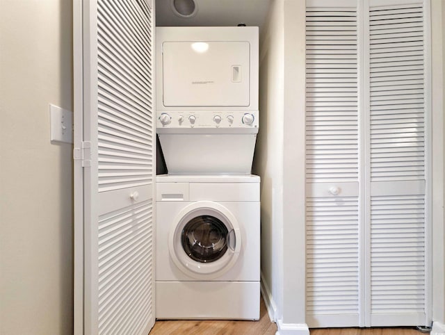 clothes washing area with light wood-type flooring, laundry area, and stacked washer / dryer