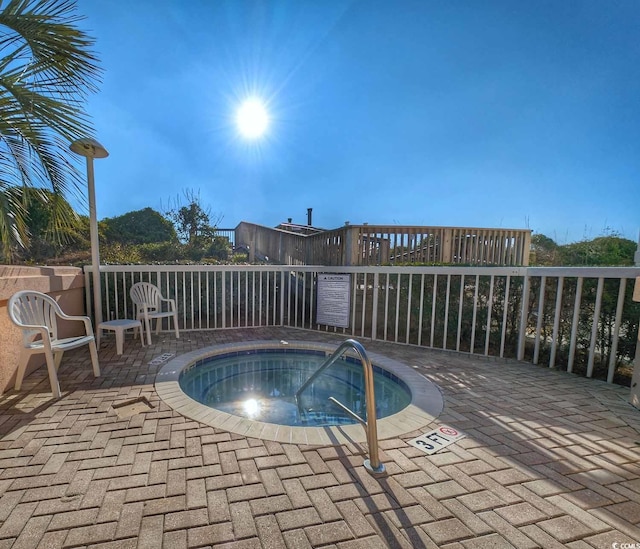 view of swimming pool featuring a community hot tub, a patio, and fence