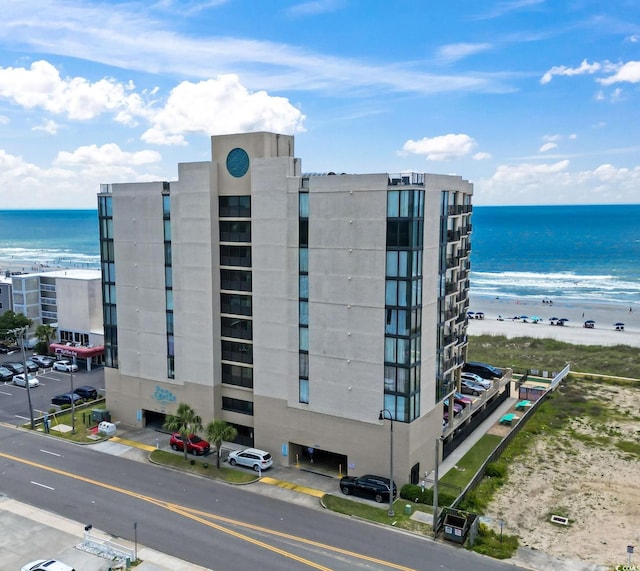 view of building exterior with a water view and a beach view