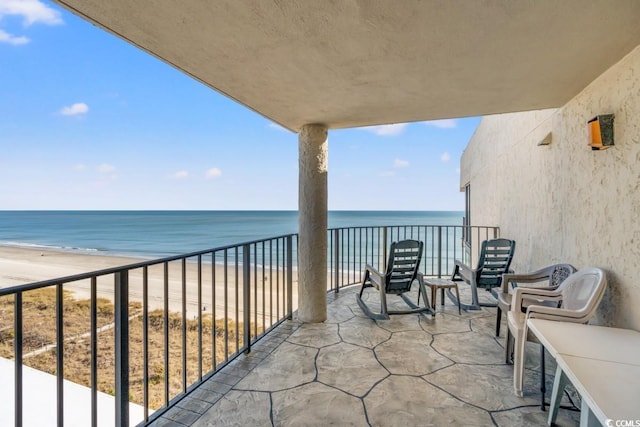 balcony with a water view and a view of the beach