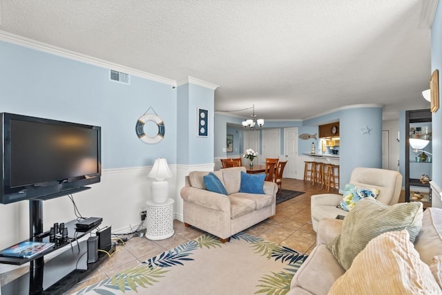 living area with light tile patterned floors, a textured ceiling, visible vents, and crown molding