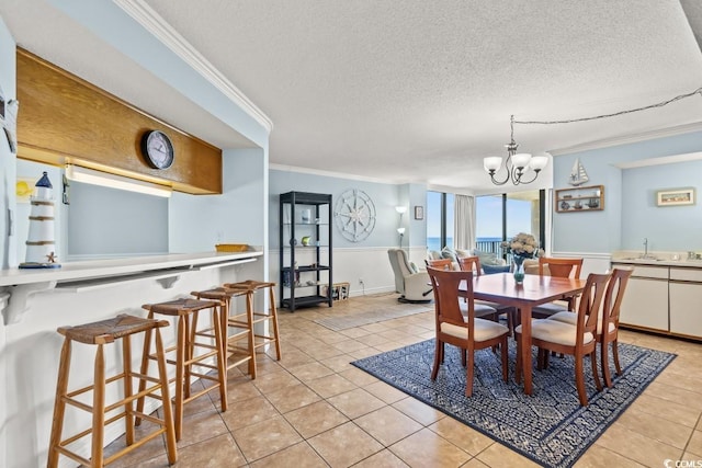 dining area with a chandelier, crown molding, a textured ceiling, and light tile patterned floors