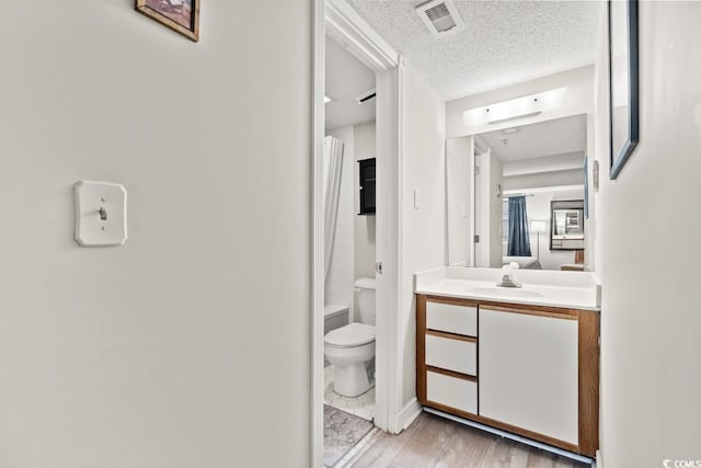 bathroom with visible vents, toilet, wood finished floors, a textured ceiling, and vanity