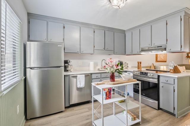 kitchen with stainless steel appliances, light wood-style floors, light countertops, and under cabinet range hood