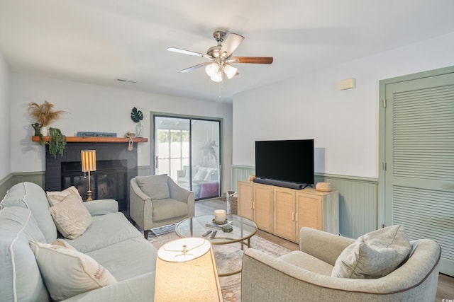 living room featuring wood finished floors, wainscoting, a fireplace, and visible vents